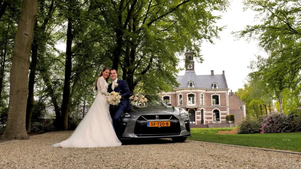 Videograaf Veenendaal - Bruidspaar met trouwauto voor landhuis