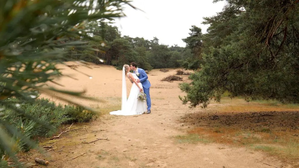 Bruidegom kust bruid met regendruppels aan boom